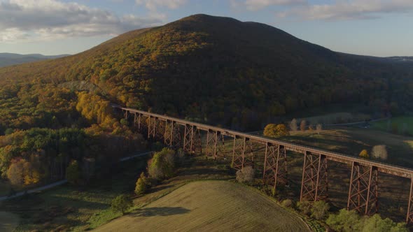 Aerial of railroad bridge passing over valley landscape on a sunny day alt