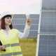 Caucasian Woman in Uniform and White Helmet Standing at Solar Farm and Holding - VideoHive Item for Sale