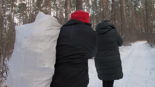 Lady Walks Along Snowy Forest Road and Lumberjack Follows