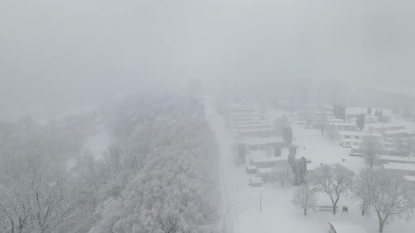 Heavy snow falling in rural Wisconsin valley over mobile home park and highway.