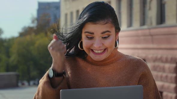 Excited Woman Student Winner Sitting Outdoors Reading Email Good News on Laptop Rejoicing Victory alt