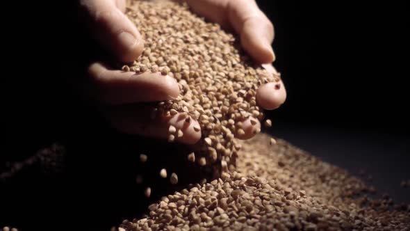 Female Hands Pours Buckwheat Grain. Slow Motion alt