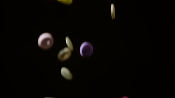 Colorful buttons falling and bouncing on black background, Ultra Slow Motion alt