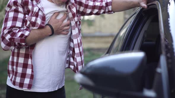 Unrecognizable Adult Caucasian Man Having Heart Attack Standing at Car Outdoors alt