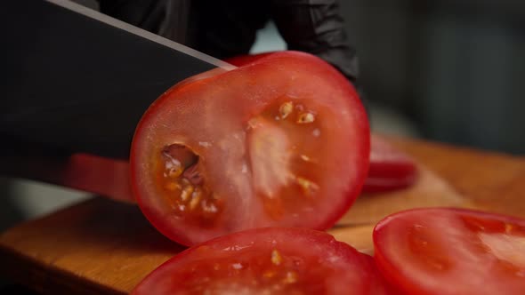Woman in Black Gloves Cuts Tomatoes at Home in the Kitchen Close Up