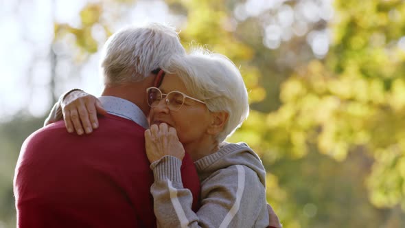 Elderly Caucasian Couple Hugging Woman Moves Her Hand Across Her Husband's Back Selective Focus Copy alt