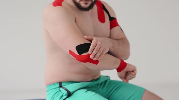 Male elbow and shoulder injuries after sports training. A kinesiology tape on an elbow of man alt