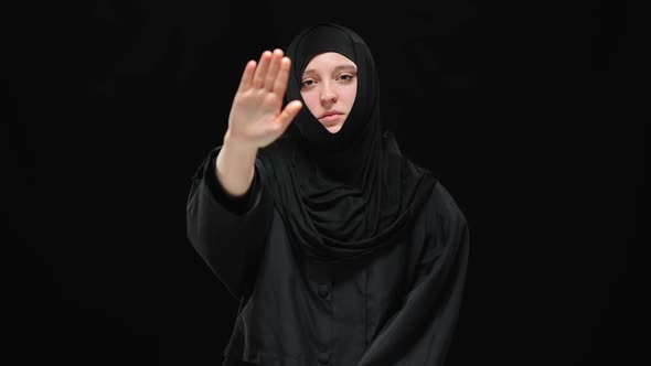Scared Stressed Muslim Woman in Hijab Raising Hand to Camera alt