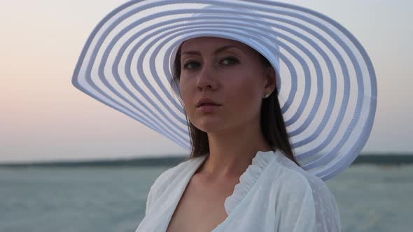 Elegant Woman with Glass of Wine Resting on Beach at Sunset