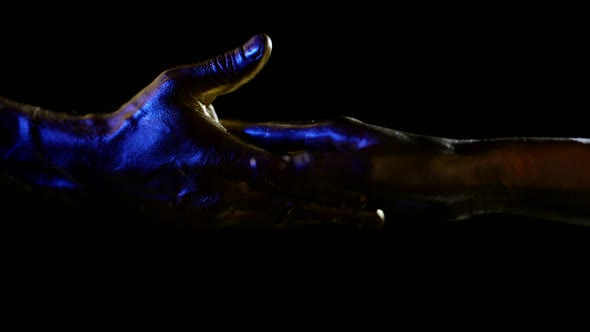 Closeup of Male and Female Hands with Metallic Golden Skin on a Black Background alt