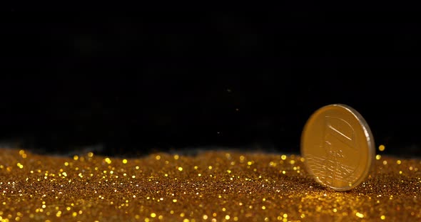 Coin of 1 Euro Rolling on Gold Powder against Black Background, Slow motion 4K alt