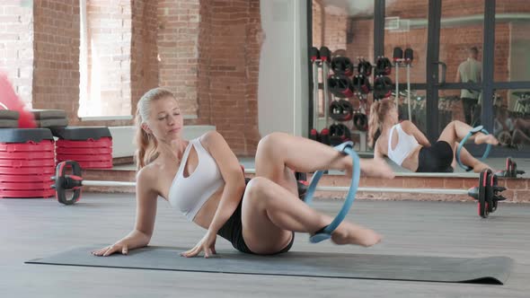 Young Caucasian Sportive Pretty Woman Doing Exercise with Pilates Ring at Gym
