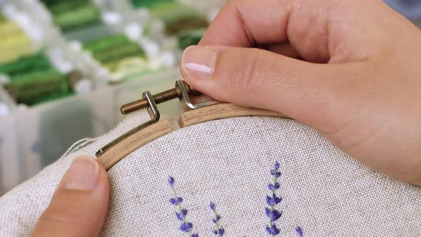 Handmade embroidery, art, woman, hobby. Woman tightens the screw of a wooden frame for embroidery