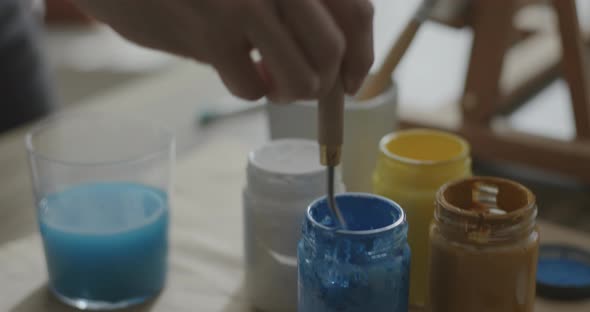 Artist mixing acrilic paint in a cup