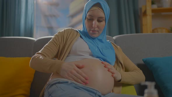 Pregnant Muslim Young Woman Uses Ointment or Body Lotion alt