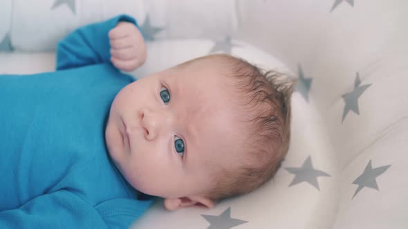 Upset Little Boy Bothers Bare Legs in Baby Cocoon with Stars alt