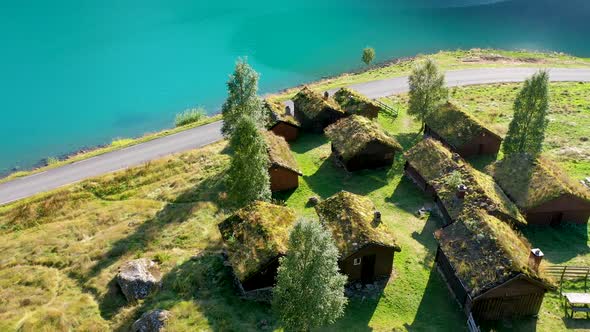 Grass roof house cluster on a meadow near a lake, Aerial view alt