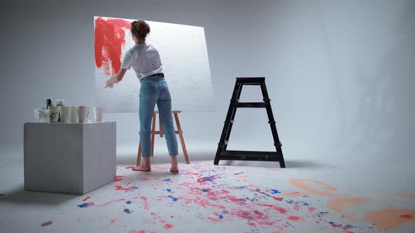 Female Artist Draws with a Brush on a Large Canvas in a White Room a Talented Artist Draws a Color alt