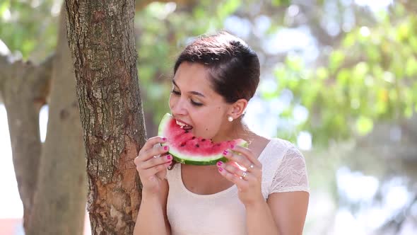 Beautiful young woman eating a slice of watermelon and smiling alt
