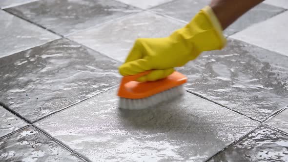 Cleaning the tiled floor with a plastic floor scrubber.