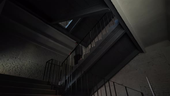 A Man in a Jacket Quickly Descends the Stairs Down in the Apartment