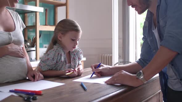 Parents helping little girl with homework in kitchen