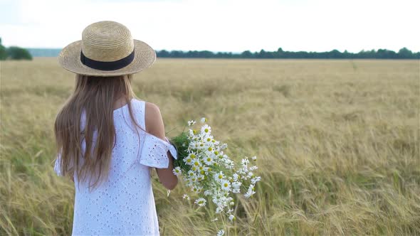 Beautiful Girl in Wheat Field with a Bouquet of Chamomile in Hands