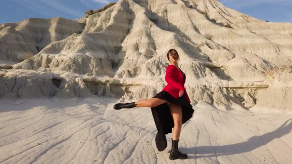 Young Girl with red jacket is dancing at a desert rock. alt