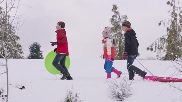Kids walking through snow with sleds in winter