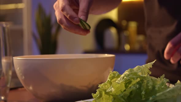 Men's Hands Throw Sliced Fresh Cucumbers Into a Salad