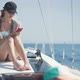 Beautiful Woman on a Yacht with Smartphone in Hands on the Background of the Islands of Ibiza or