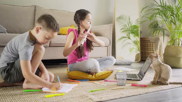 Boy Draws in Notebook Girl Plays Flute at Laptop Near Cat