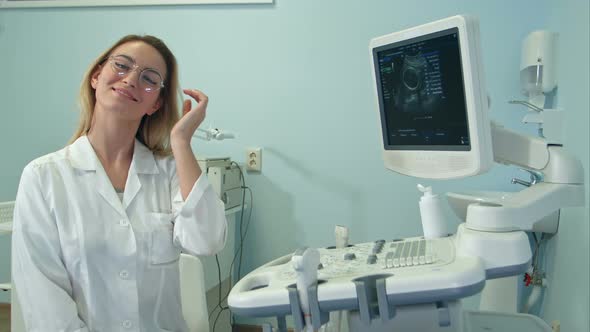 Smiling Female Doctor in Glasses Looking Into the Camera in Ultrasound Room alt
