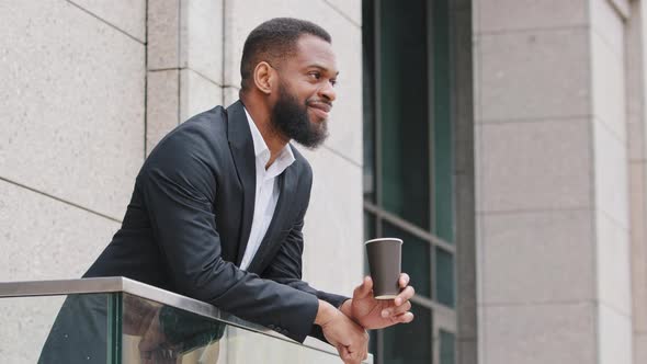 Smiling Young African American Corporation Employee Manager Businessman Drinking Coffee on Balcony alt