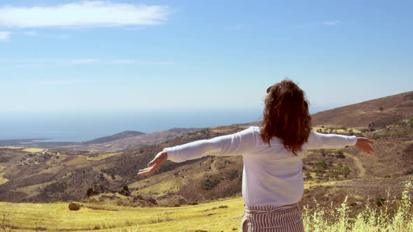 Woman worshipping with hands in the air on top of the mountain