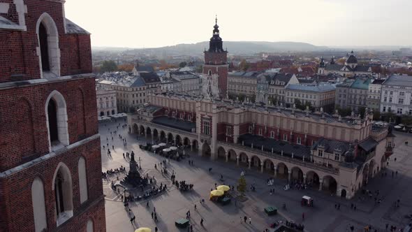 Aerial flying backwards from Renaissance Cloth Hall revealing St. Mary's church, Krakow alt