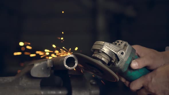 man works with a circular saw. Sparks fly from the hot metal. alt