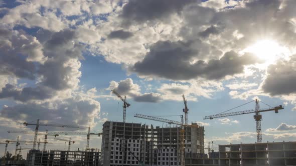 Cranes at a Construction Site and Sunlight Shining Through the Clouds