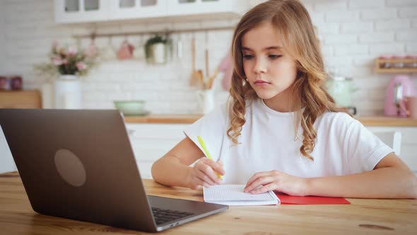 Portrait of Cute Little Girl Sitting at Kitchen Table Using Laptop for Distance Learning Slow Motion alt