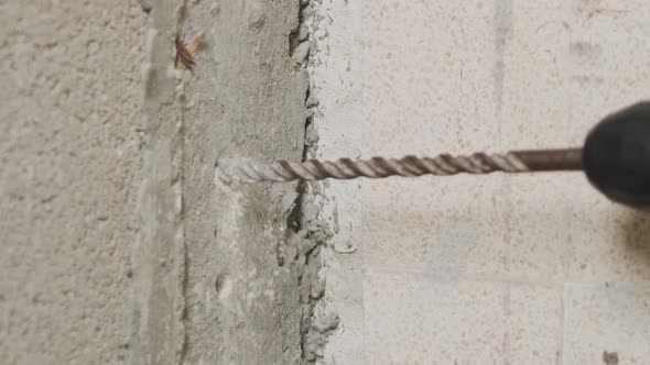 Man drilling hole in concrete wall. Repair works indoors in slow motion alt