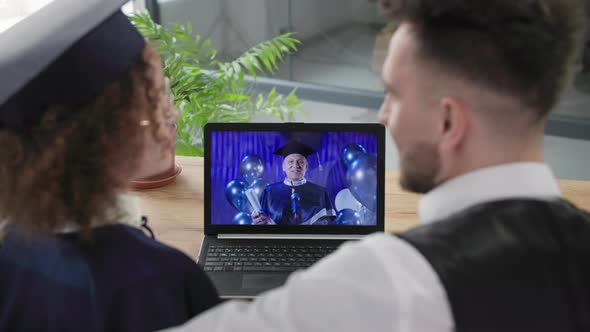 Young Married Couple with Female Graduate Watch Graduation Online with Male Teacher Via alt