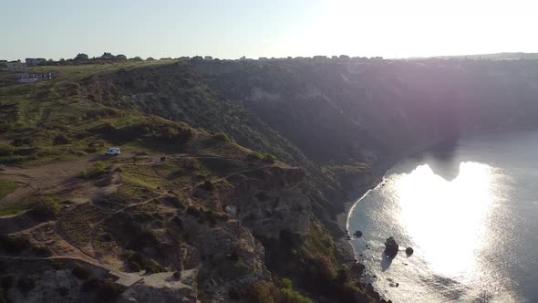 Drone footage of a cliff at sunrise with sea