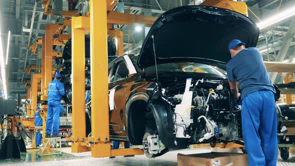 Car Mechanic Assembling a Car at a Car Manufacturing Plant alt
