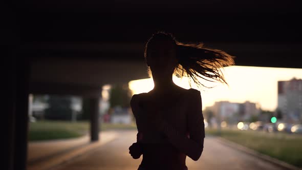 A Young Woman Runner is Training in the Summer Within a City alt