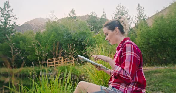 Young Woman on Outdoor Adventure. Traveler with Backpack Exploring Map of Forest alt