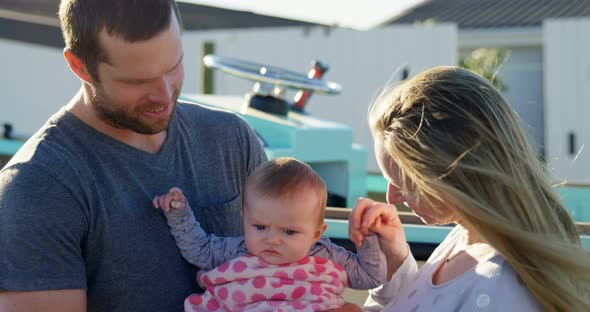 Parents holding baby boy at backyard alt