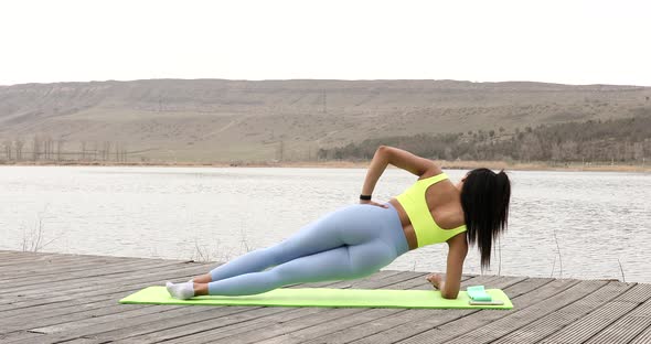 Athletic young woman standing in plank exercising.