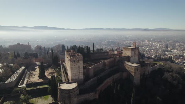 Exterior walls of Alhambra with foggy landscape in background, Granada in Spain. Aerial drone panora