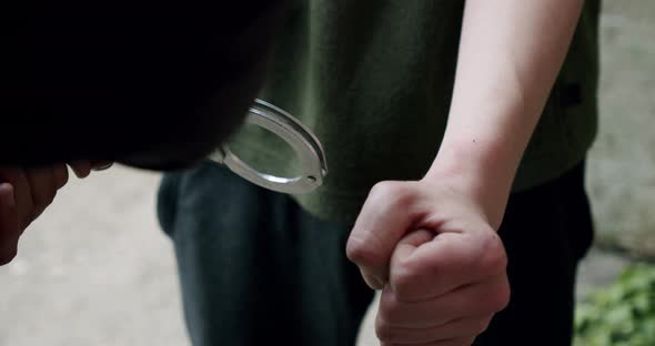 The Criminal Is Handcuffed and Held in Front Close Up. alt
