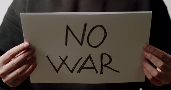 Person Holding a White Paper with a Message No War alt